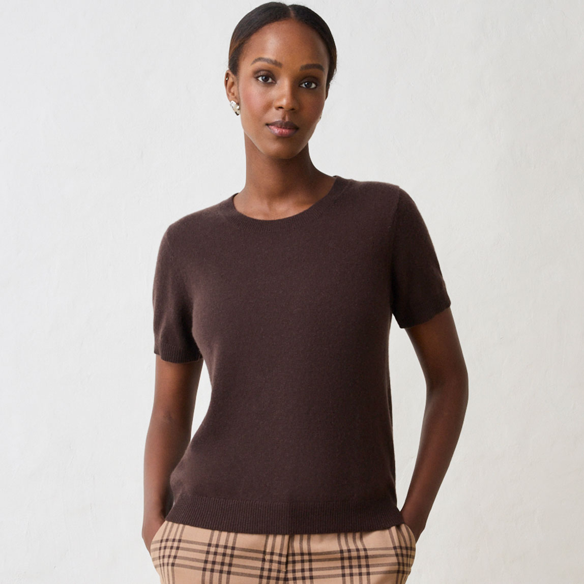 Dunkelbrauner Kurzarm-Pullover und karierte Hose.