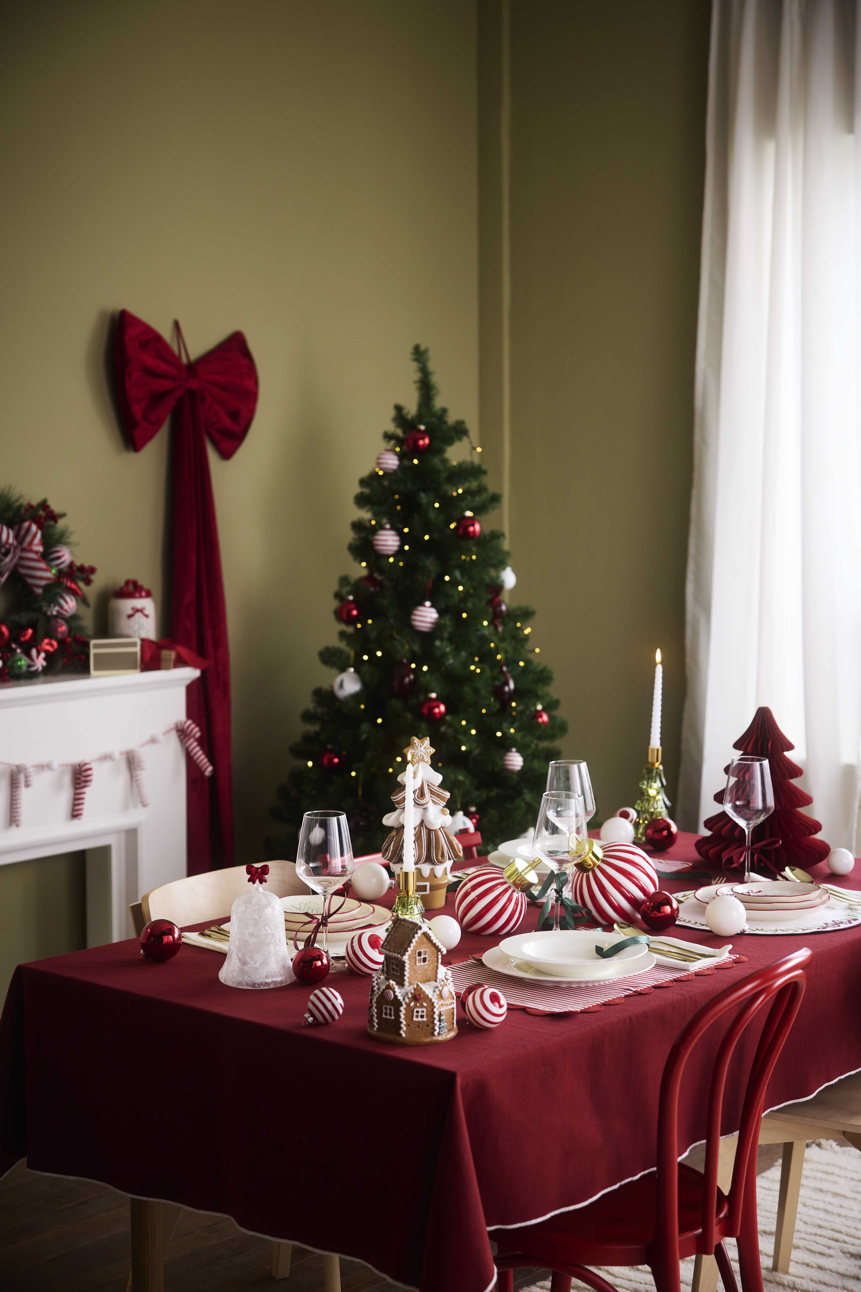 Rote Tischdecke, Weihnachtsbaum, Lebkuchenhaus und festliche Dekoration schaffen Weihnachtsstimmung.