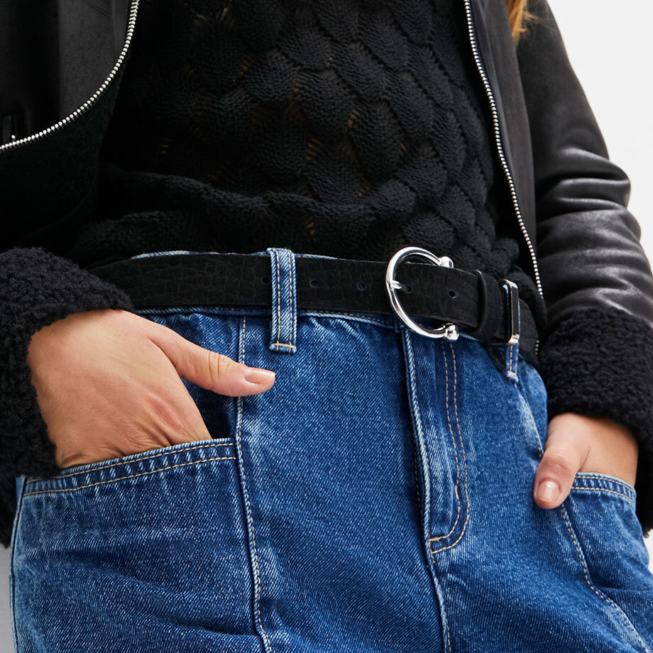 Schwarze Lederjacke trifft auf klassische Jeans. Stilvoller Kontrast mit silbernem Gürtel und Reißverschluss.