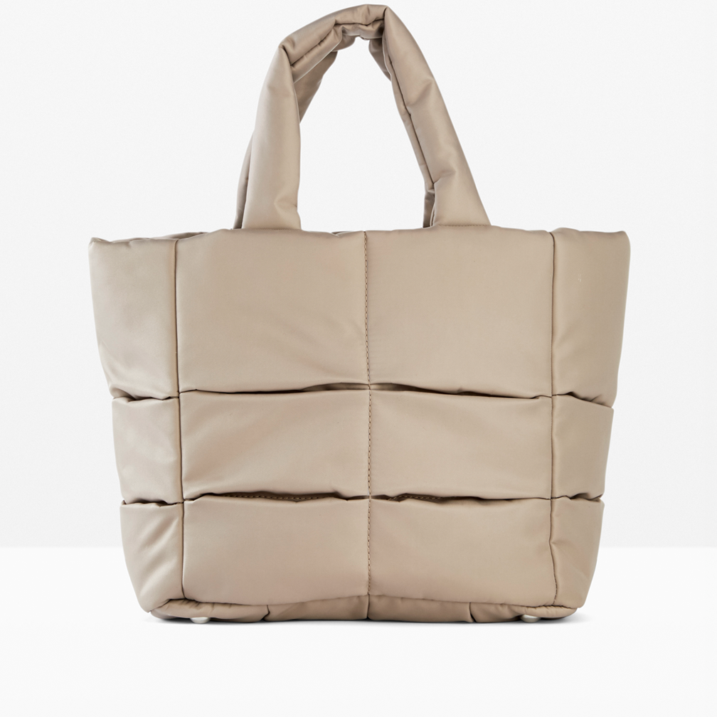 Eine gepolsterte Handtasche in Beige mit strukturiertem Design und kurzen Henkeln.