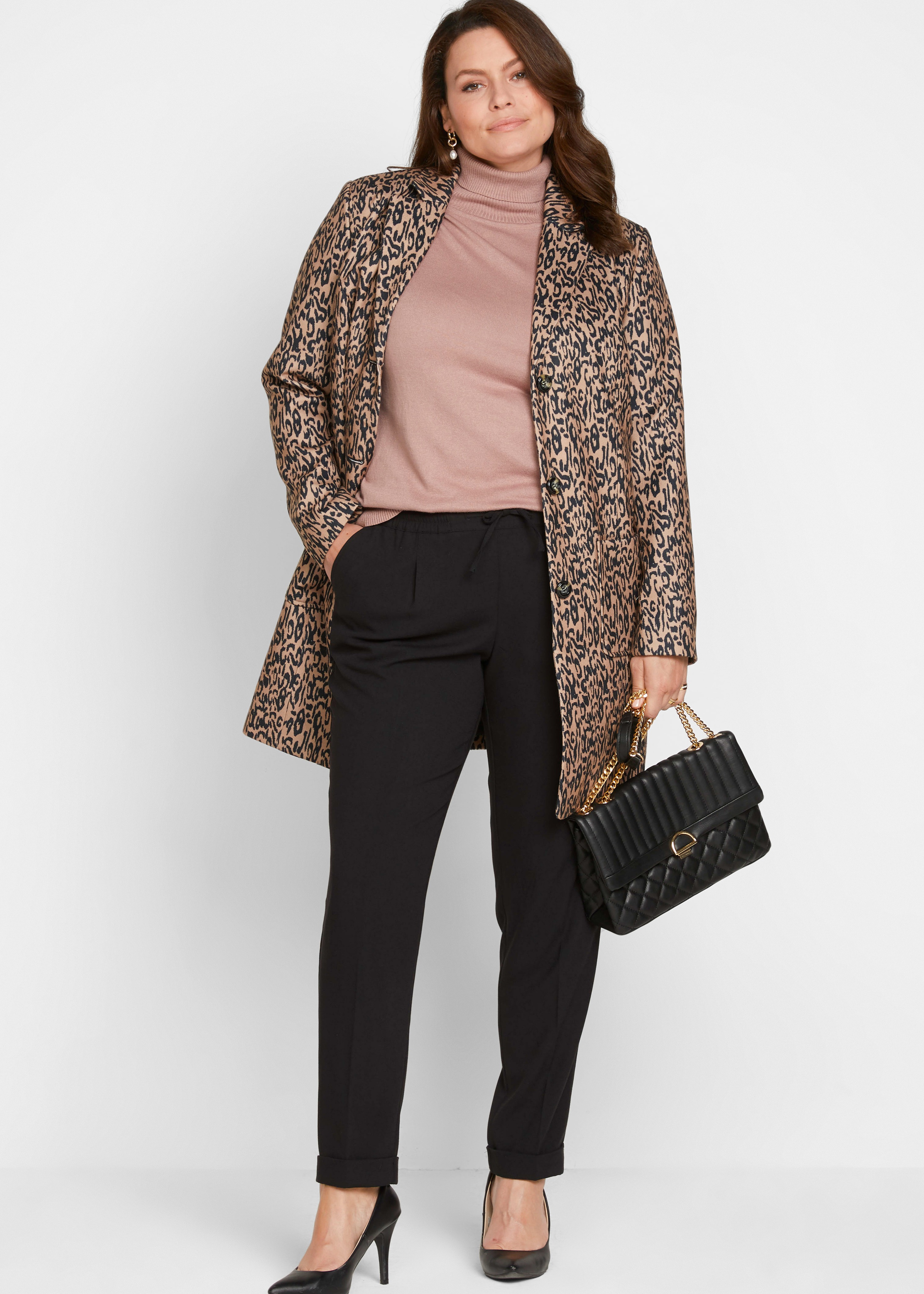 Stilvoller gemusterter Mantel, rosafarbener Pullover, schwarze Hose, Pumps und Handtasche.