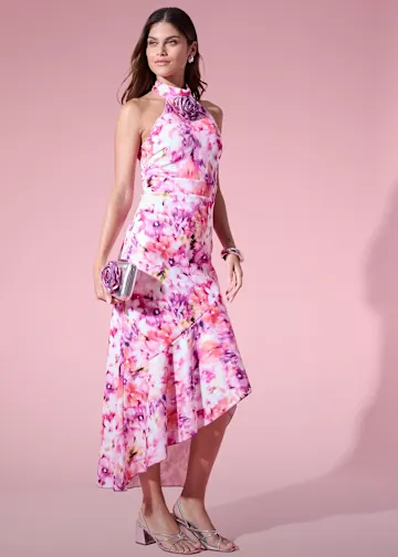 Elegantes Neckholder-Kleid mit Blumenmuster, dazu silberne Clutch und Sandalen.