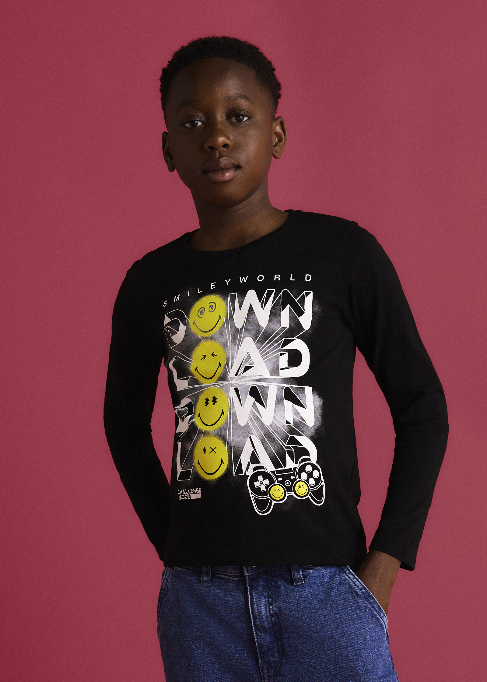 Der Junge trägt ein schlichtes weißes T-Shirt und bequeme blaue Jeans.