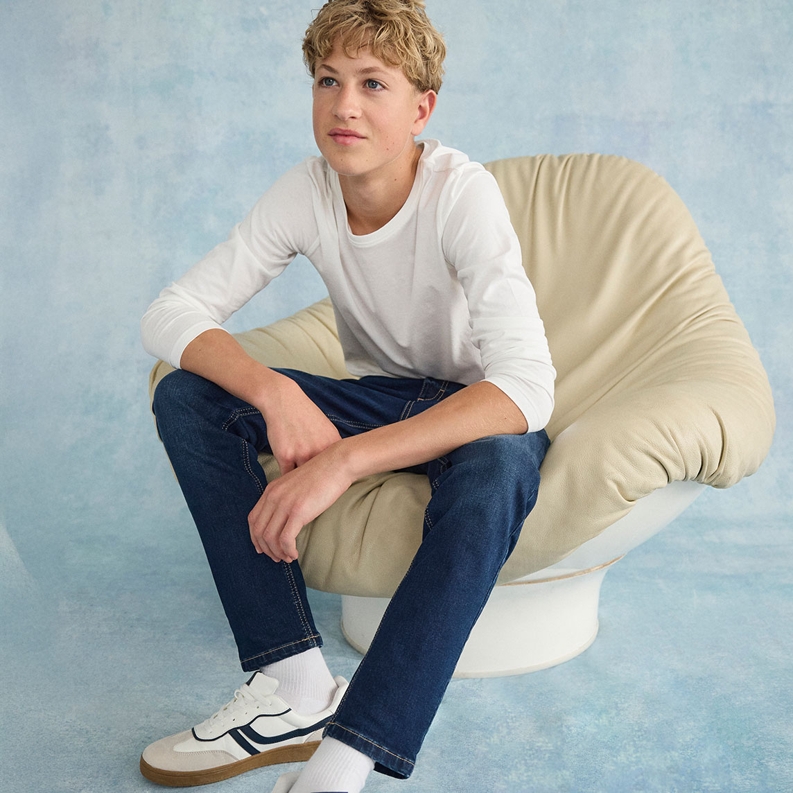 Weißes Langarmshirt, dunkle Jeans und weiße Sneakers.