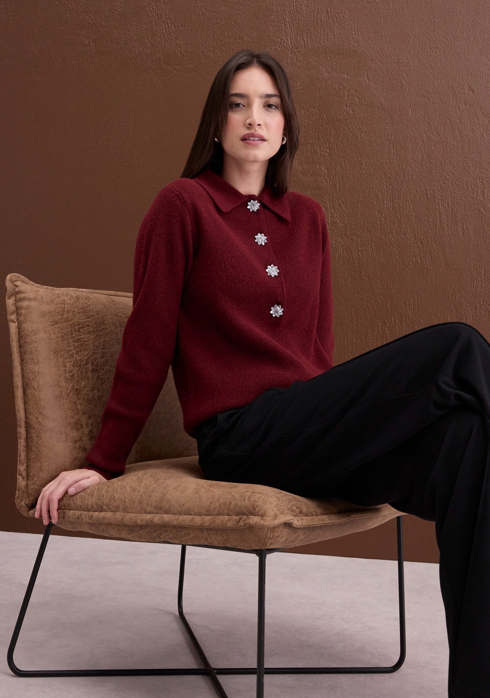Bordeauxrote Strickjacke mit funkelnden Blumenknöpfen und dazu schwarze Hose.