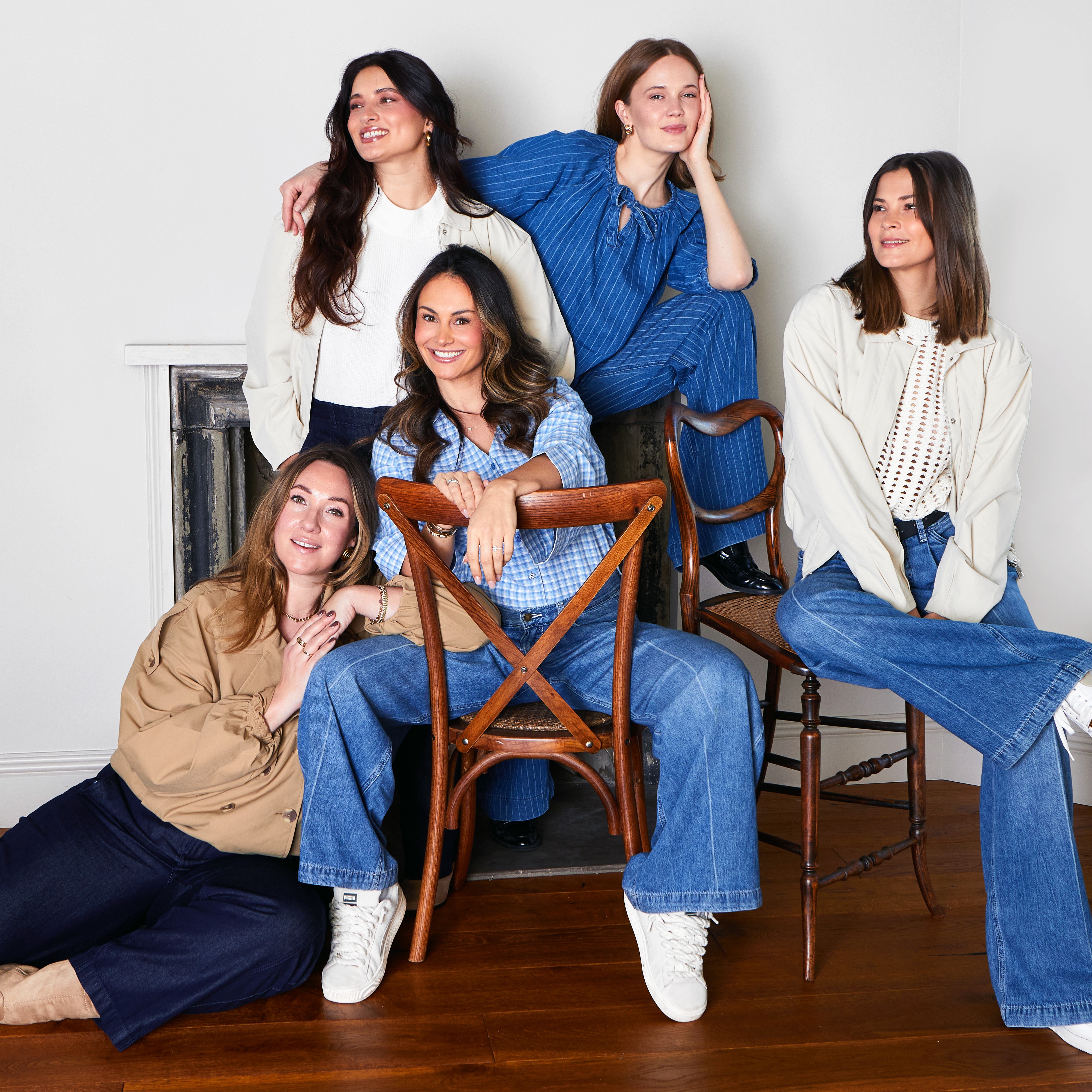 Lässige Jeans, blaue Hemden und weiße Oberteile dominieren die entspannte Gruppenaufnahme.