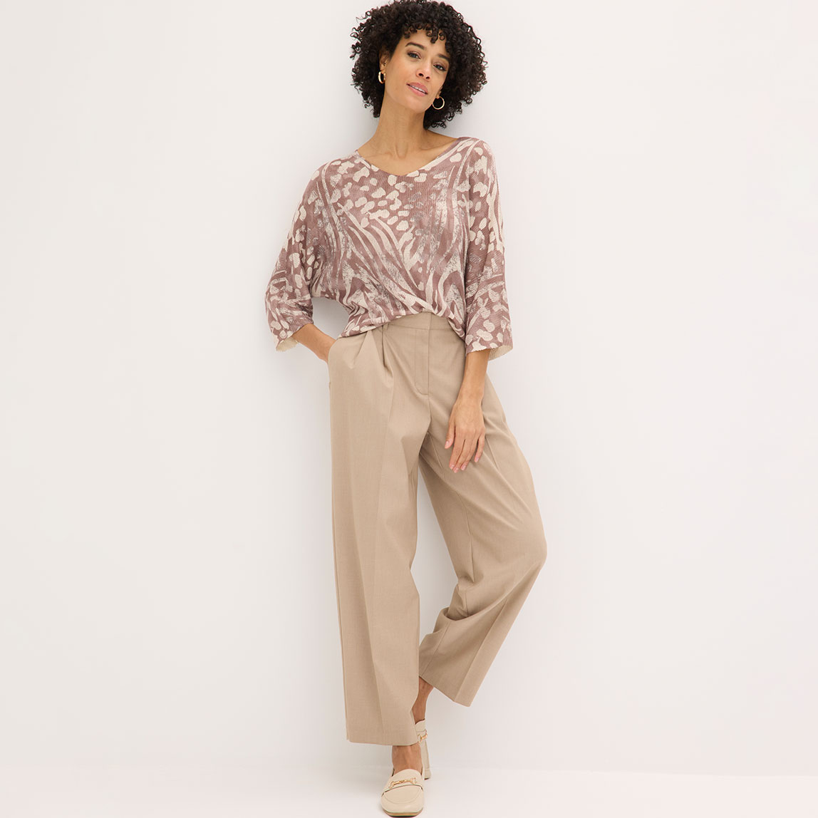Gemusterte Bluse mit weiter beiger Hose und passenden Schuhen.