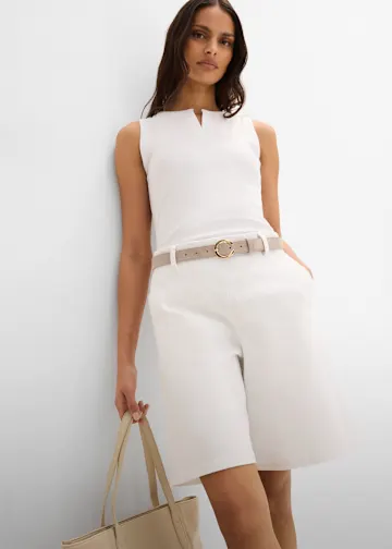 Weißes Tanktop und weiße Bermudas, akzentuiert mit beigem Gürtel.