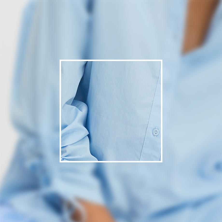 Hellblaues Hemd im Fokus, elegant und luftig. Knöpfe und Kragen sichtbar, professioneller Look.