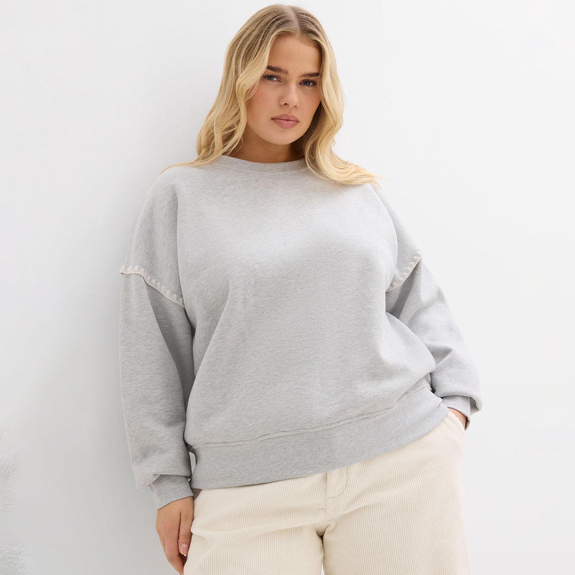 Graues Sweatshirt, kombiniert mit heller Hose.