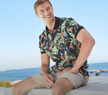 Farbenfrohes Poloshirt mit Blumenmuster und helle Shorts.