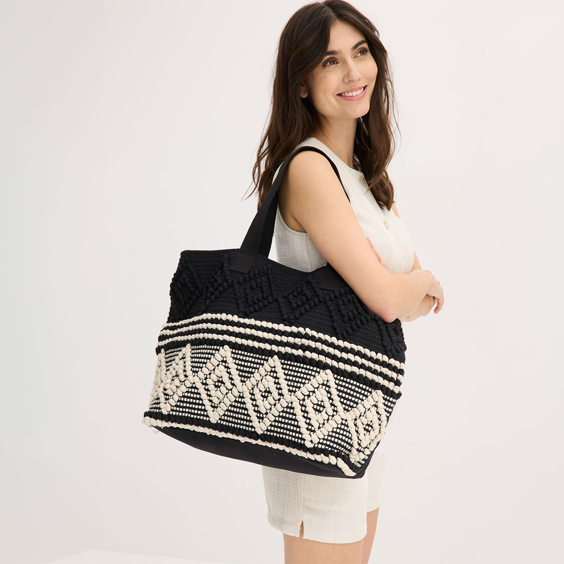 Helles, strukturiertes Outfit und eine auffällige, schwarz-weiß gemusterte Tasche.