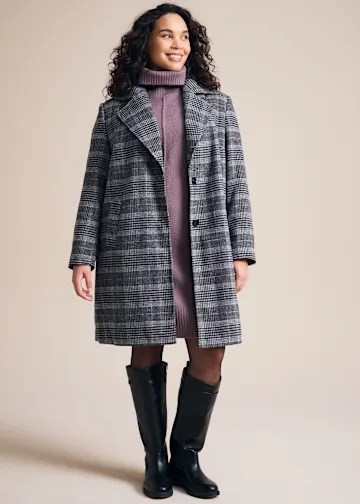 Lila Rollkragenkleid, karierter Mantel, schwarze Strumpfhose und Stiefel.