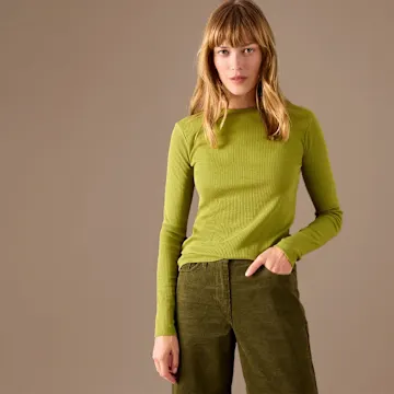 Grünes Langarmshirt trifft bequeme Cordhose – ein harmonischer Look in Erdtönen.