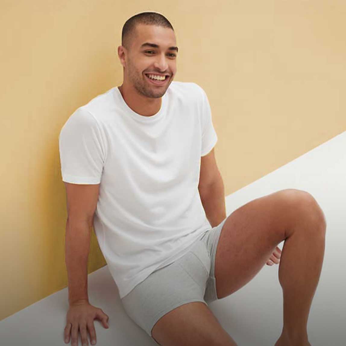 Ein Mann trägt ein weißes T-Shirt und helle Shorts in entspannter Sommerkleidung.