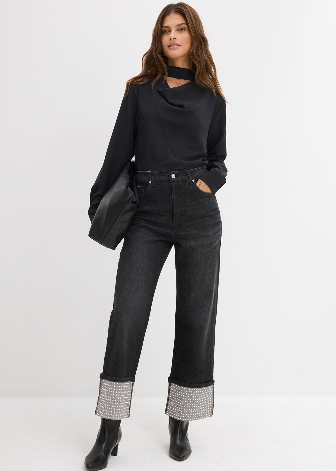 Schwarzer Pullover, kombiniert mit weiten Jeans und kontrastierenden Umschlägen.