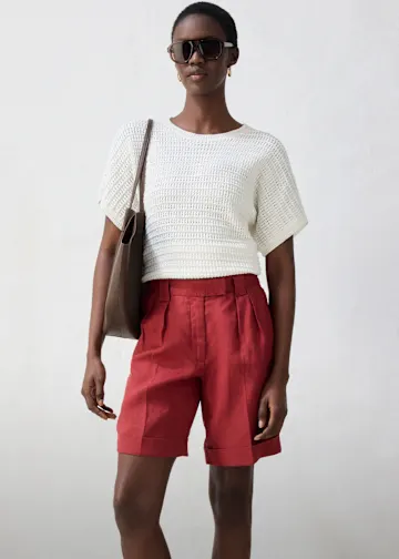 Kombination aus weißem Oberteil und roter Bermudashorts.