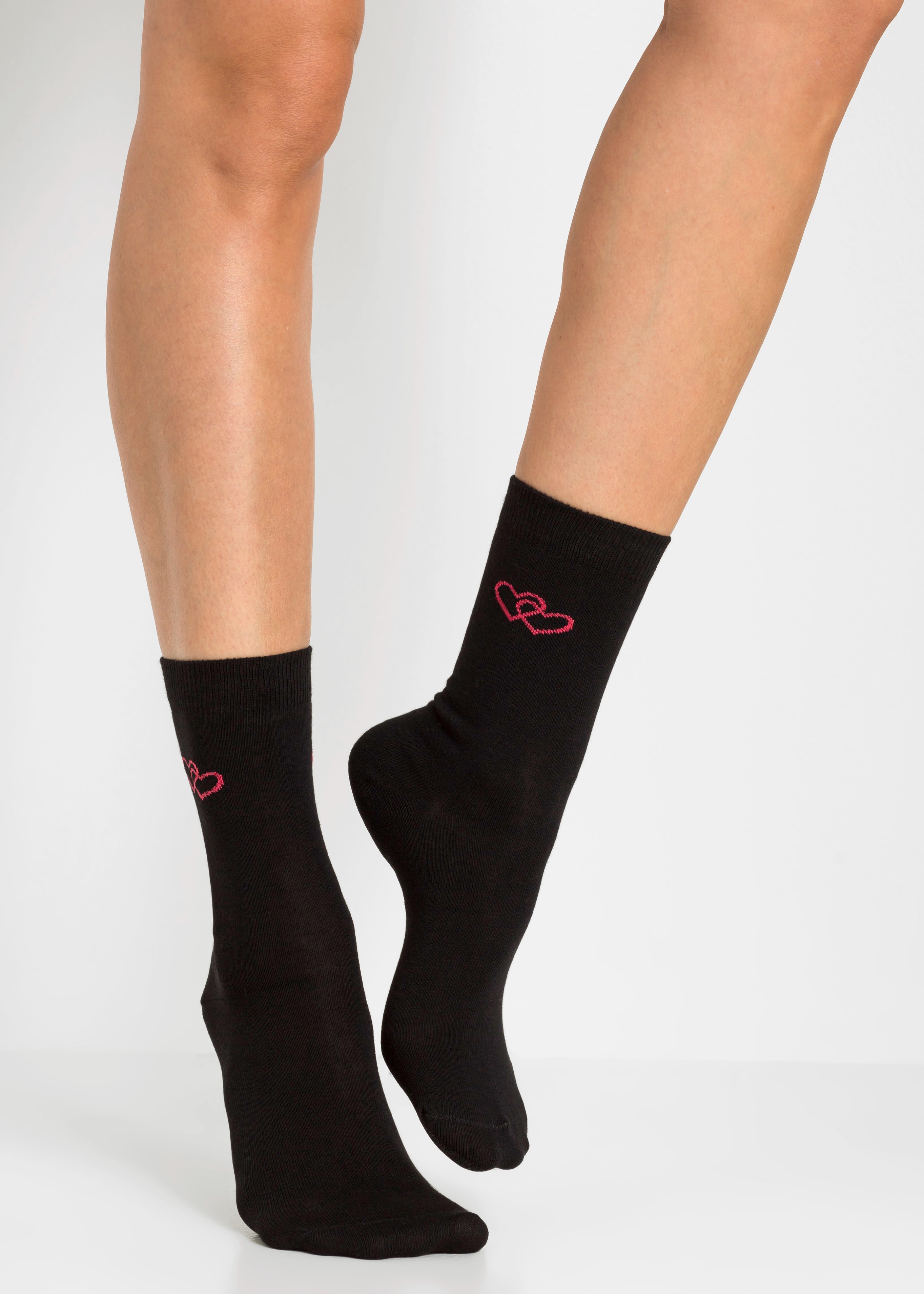 Die Füße tragen schwarze Socken, verziert mit süßen pinken Herzen.