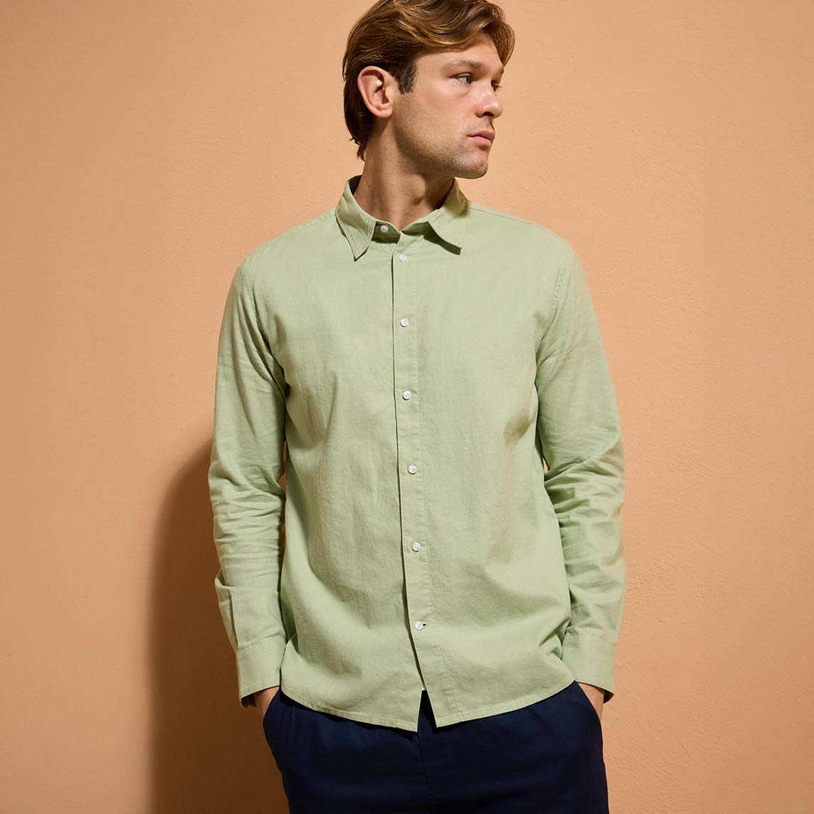 Ein hellgrünes Hemd kombiniert mit dunkelblauer Hose.