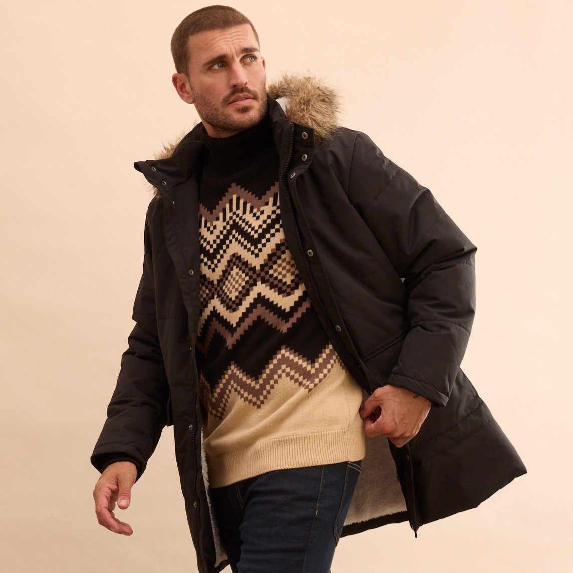 Warmer Wintermantel mit Pelzkragen, darunter gemusterter Pullover und helle Hose für kalte Tage.