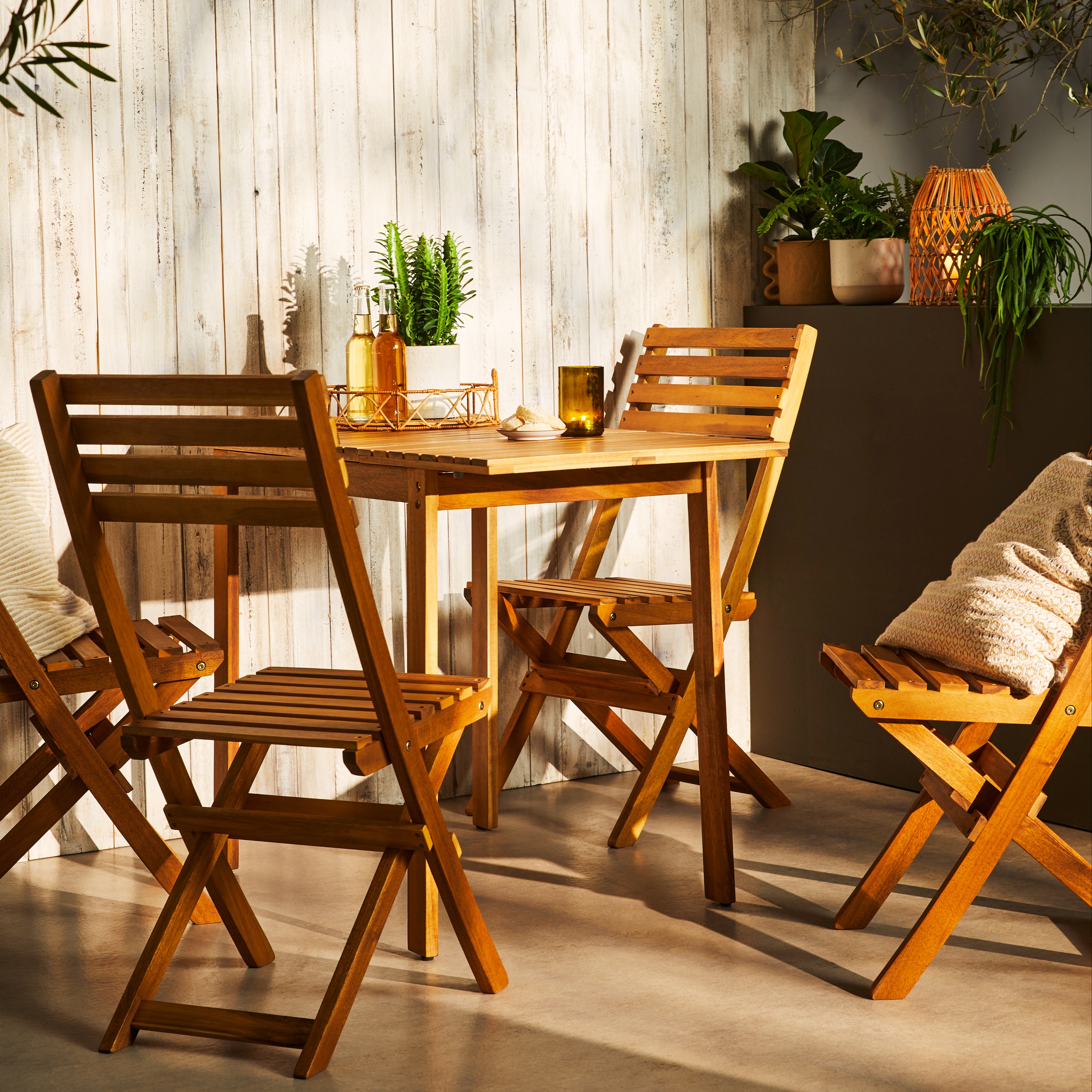 Gemütliche Holzmöbel auf der Terrasse: ein runder Tisch mit passenden Klappstühlen für entspannte Sommerabende.