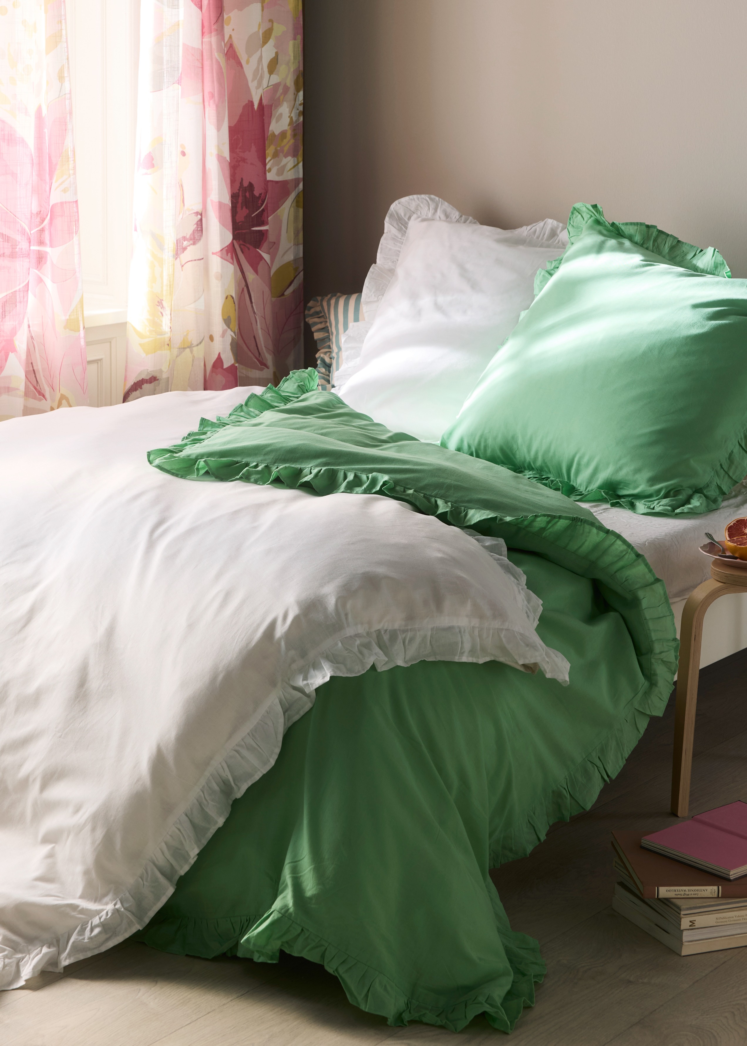 Bettwäsche in Weiß und Grün schmückt das gemütliche Bett.