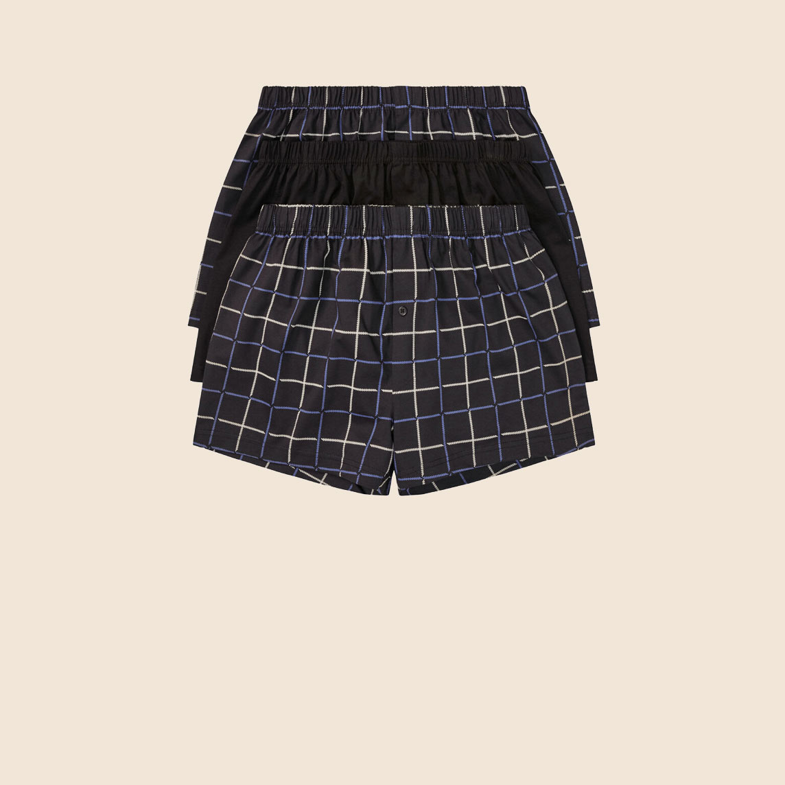 Zwei Boxershorts: eine schlicht schwarz, eine mit modernem Karomuster.