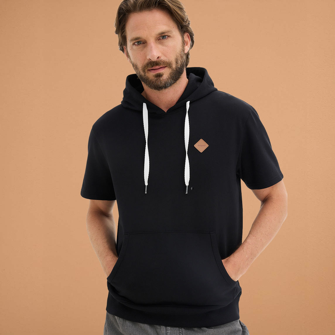 Schwarzer Hoodie mit kurzen Ärmeln & weißen Kordeln und orangefarbenem Logo.