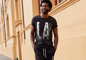 Lässig in schwarzem T-Shirt mit „LA“-Print und passender Jogginghose gekleidet.