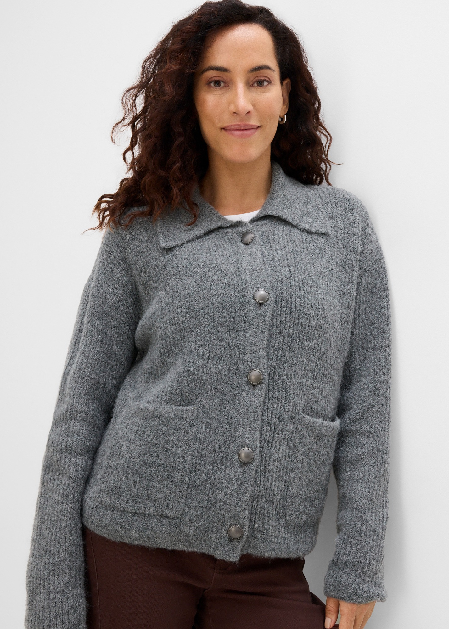 Eine warme, graue Strickjacke mit Kragen, Knöpfen und aufgesetzten Taschen.