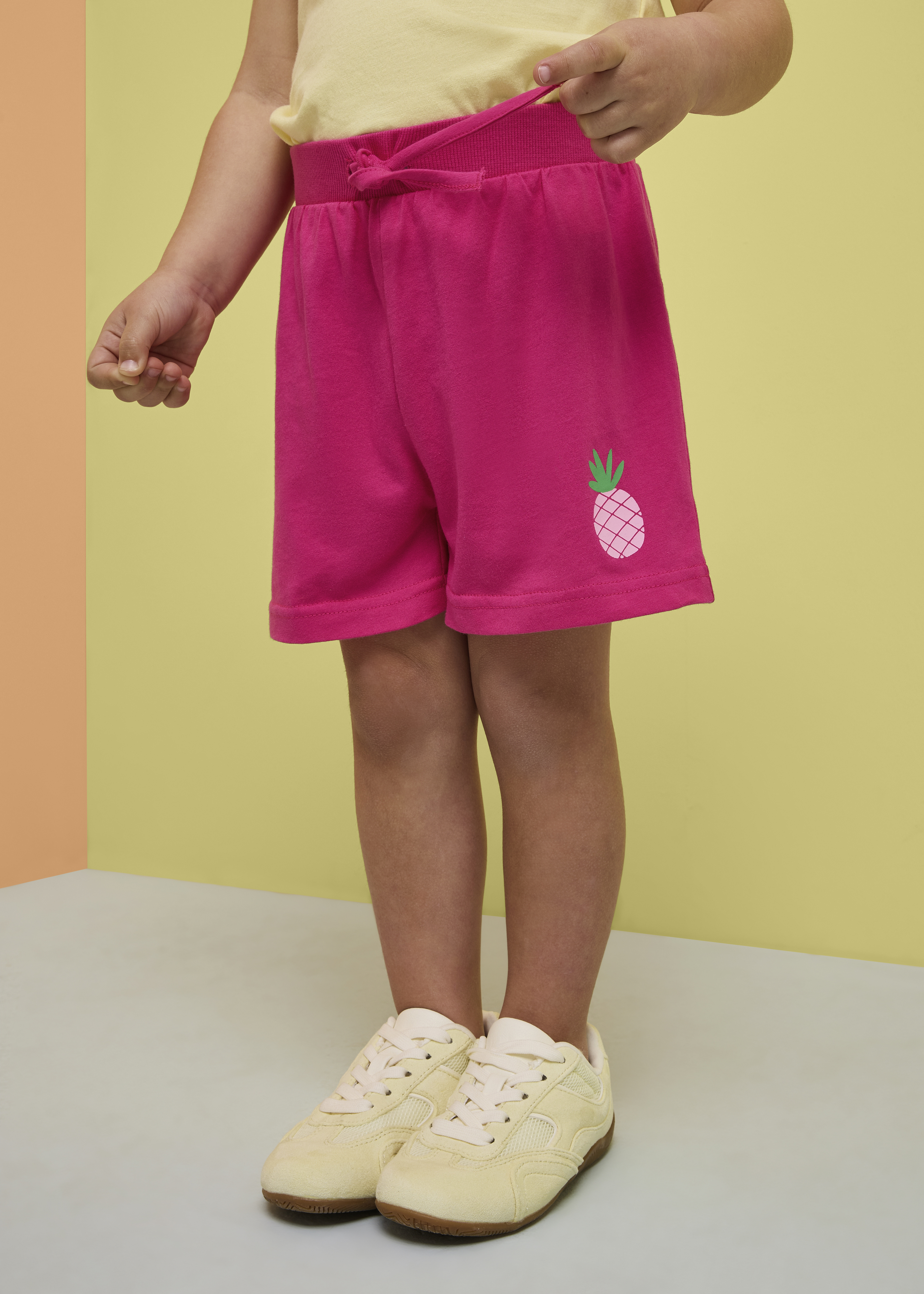 Pinke Shorts mit Ananas-Motiv und helles Oberteil.
