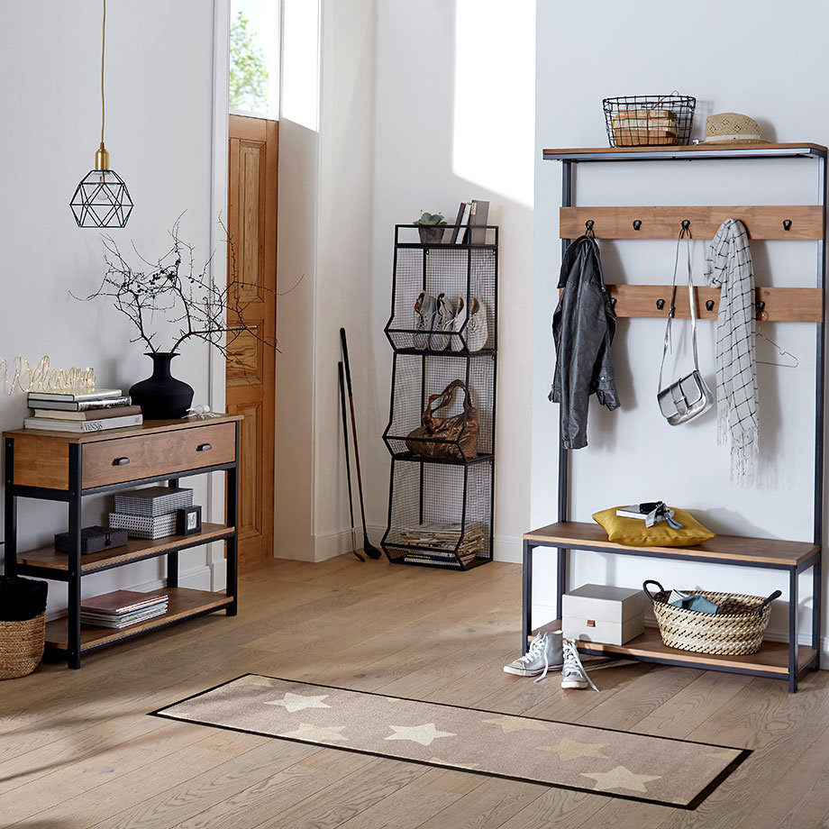 Eine Garderobe mit Haken zeigt Jacken und Taschen. Darunter steht ein Schuhregal aus Holz.