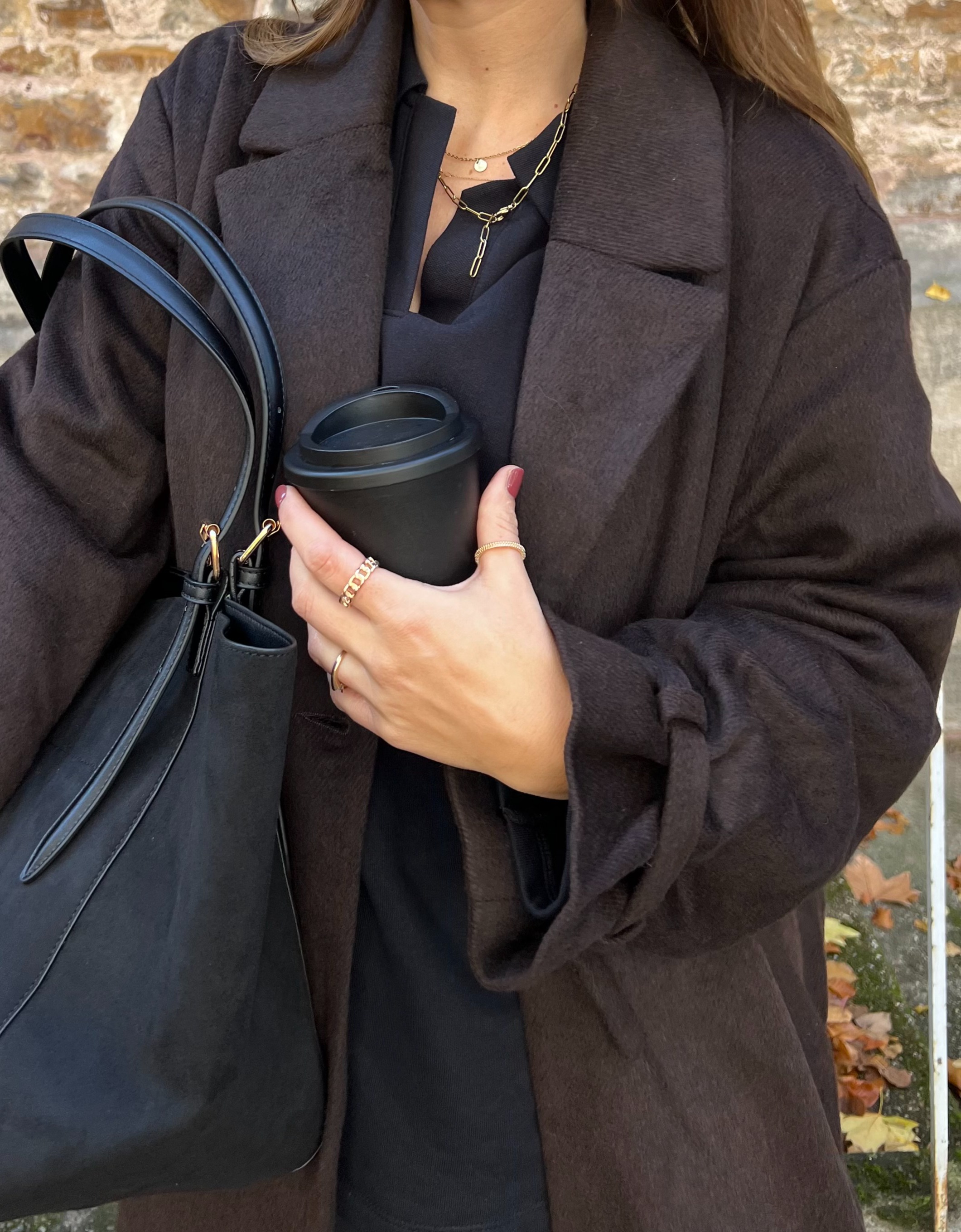 Eleganter dunkler Mantel mit goldener Halskette.