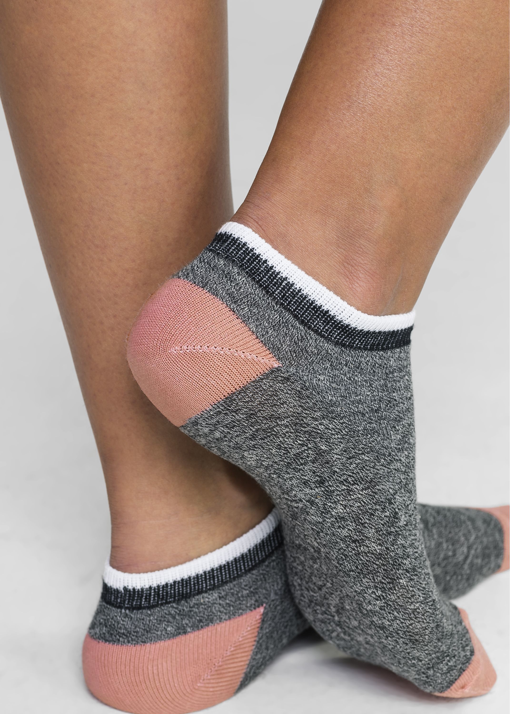 Graue Sneaker-Socken mit rosa Ferse und weißen, schwarzen Bündchenstreifen.