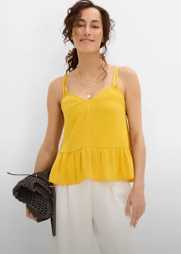 Gelbes Trägertop, weite weiße Hose und eine braune Tasche.