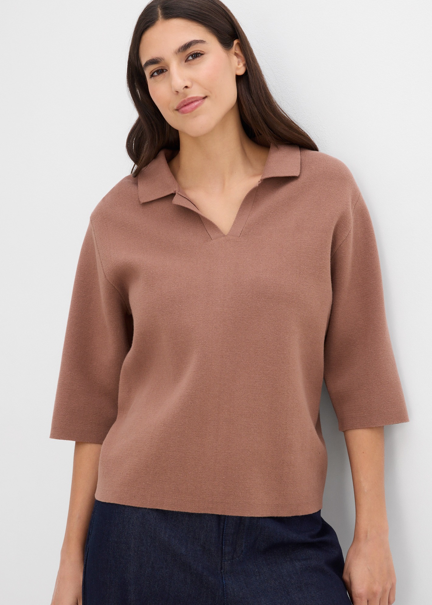 Modisches braunes Strick-Poloshirt mit Dreiviertelärmeln und dunklem Rock.