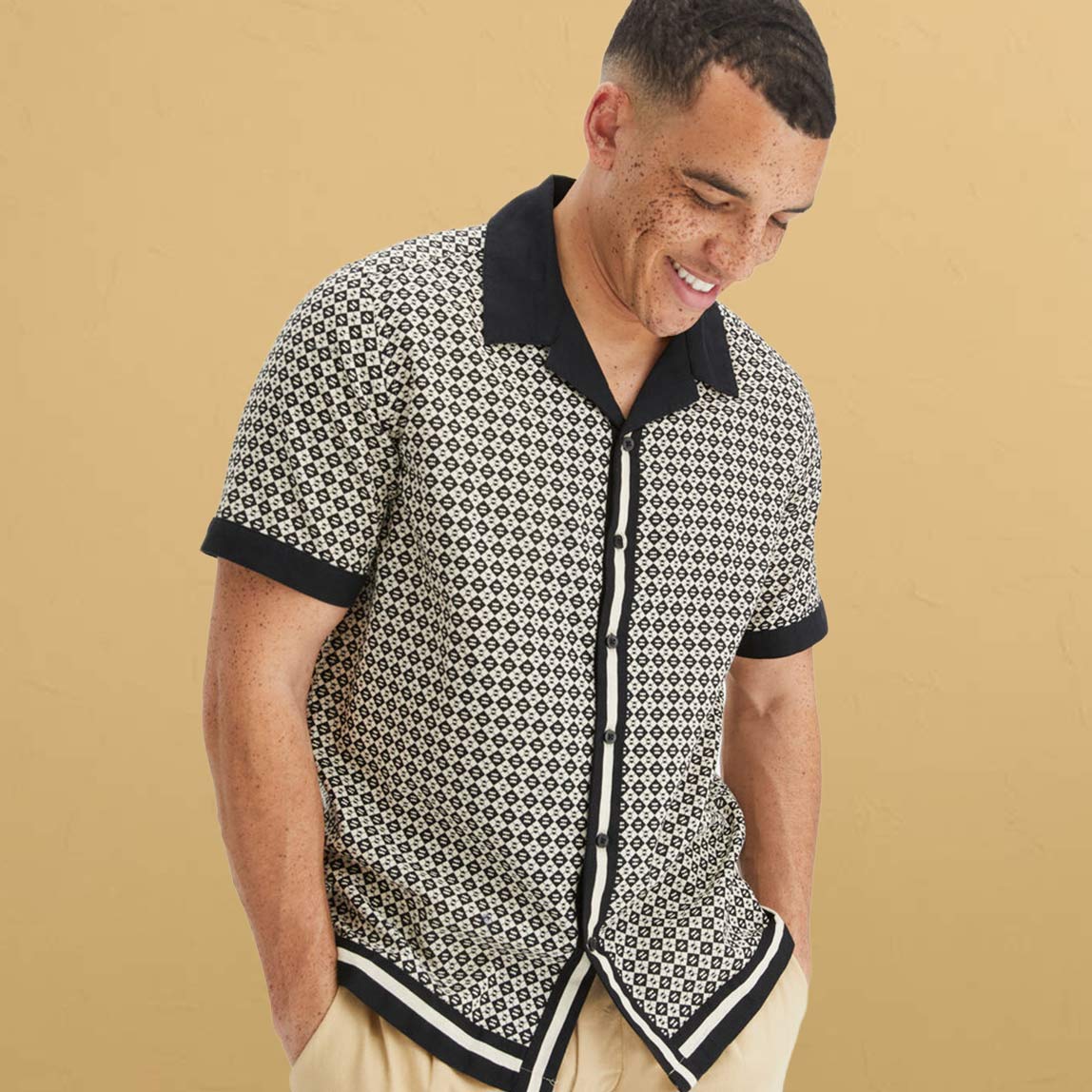 Eleganter, schwarzer Mantel, grauer Pullover und dunkler Hose. 