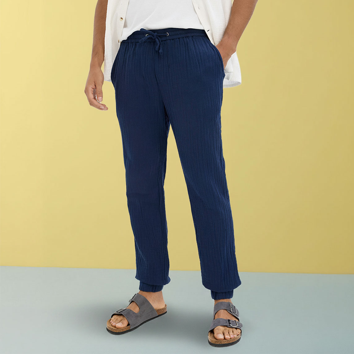 Lässige dunkelblaue Hose kombiniert mit weißem T-Shirt und grauen Sandalen.