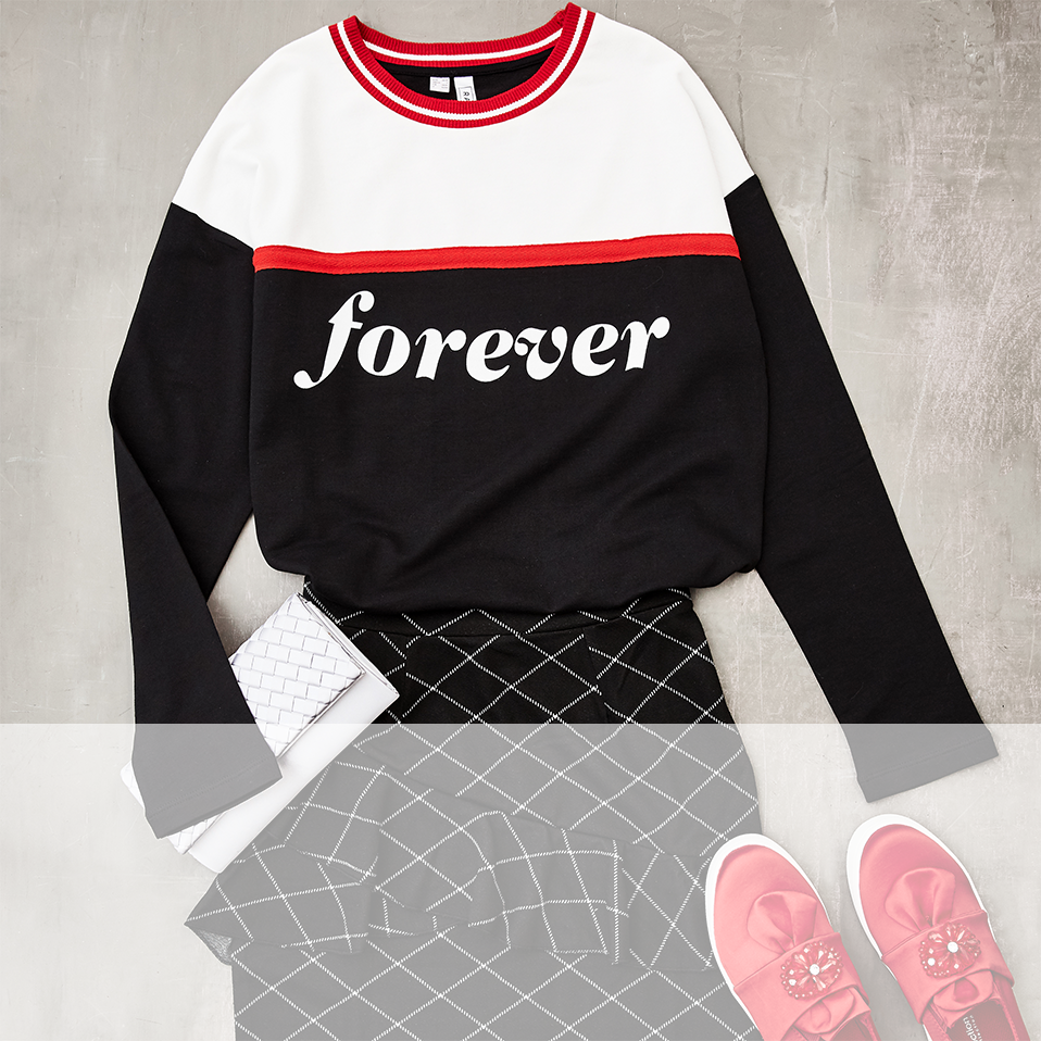 Sportlicher Pullover mit "Forever"-Aufschrift, kombiniert mit gemustertem Rock und rosafarbenen Sneakers.