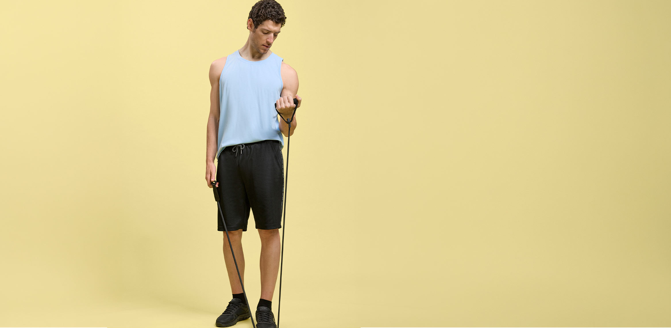 Hellblaues Tanktop, schwarze Shorts und Sportschuhe – ideal für Training.