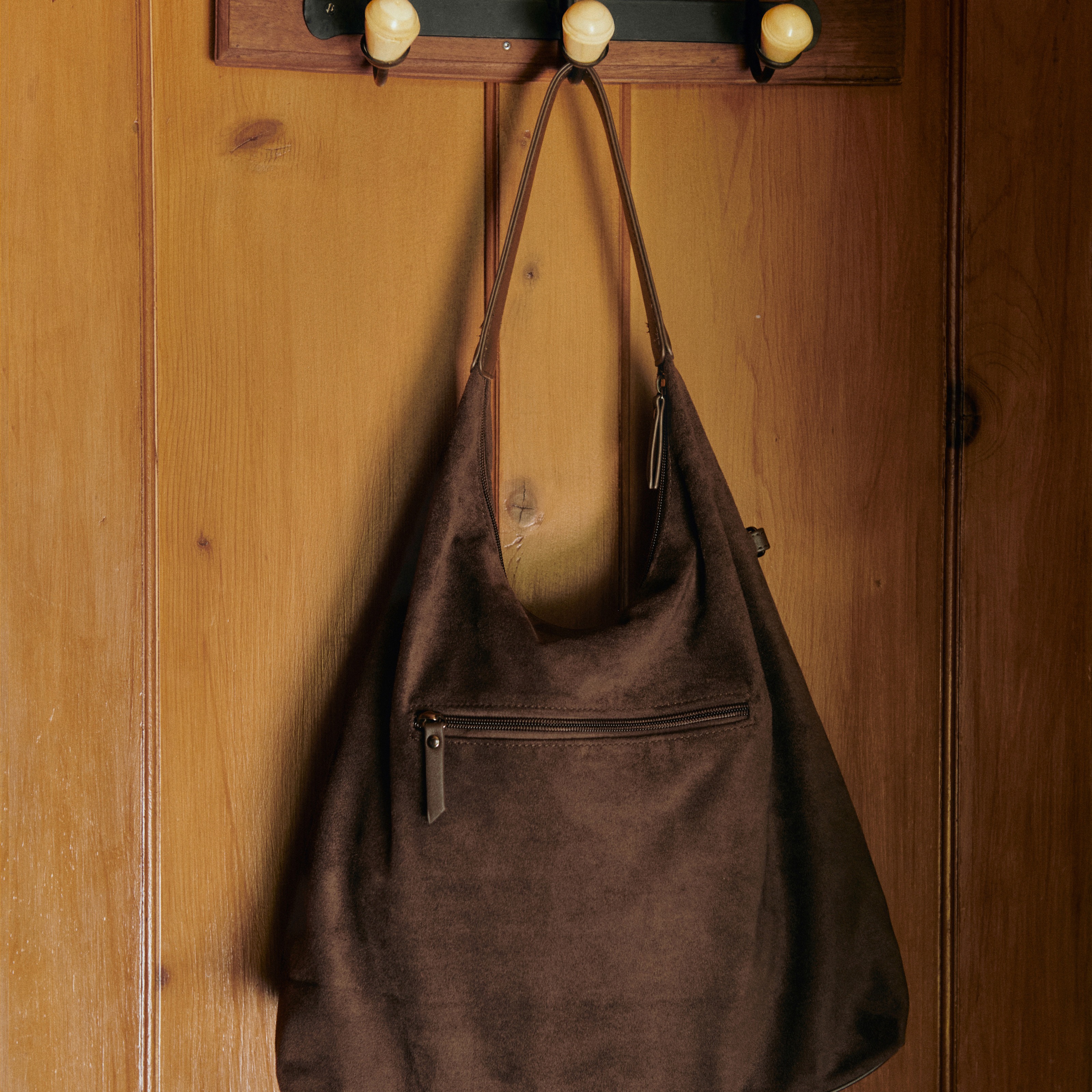 Eine stilvolle braune Tasche hängt an der Holzwand. Praktisch und elegant.