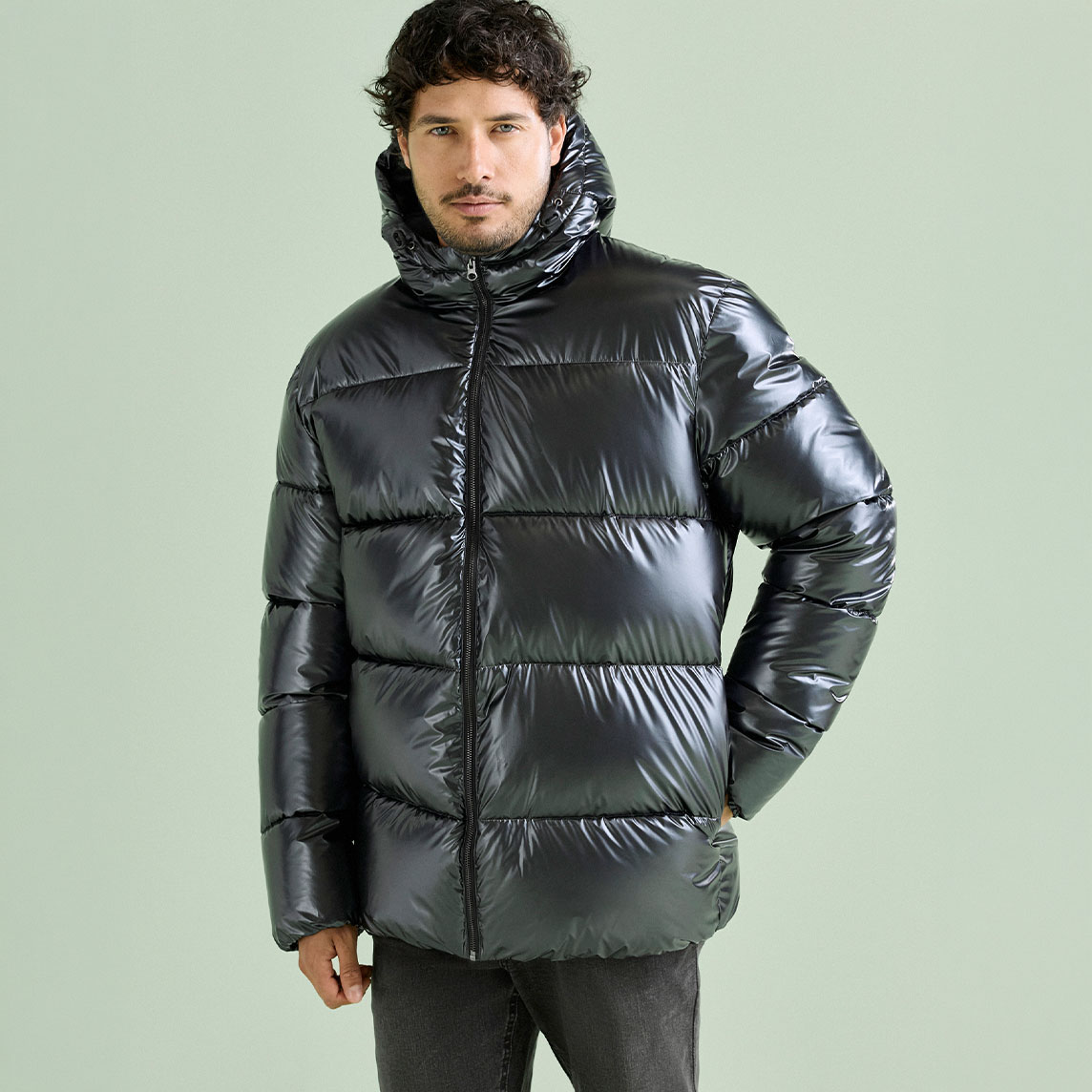 Glänzende, schwarze Daunenjacke mit Kapuze und dunkle Hose, ein lässiger Look.