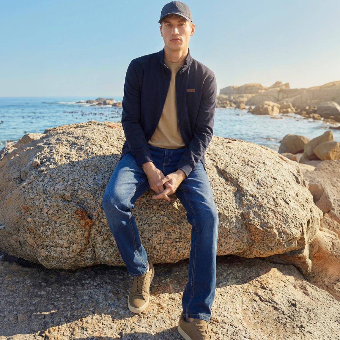 Blaue Jacke, beiges Shirt und Jeans für sonnige Tage am Meer.