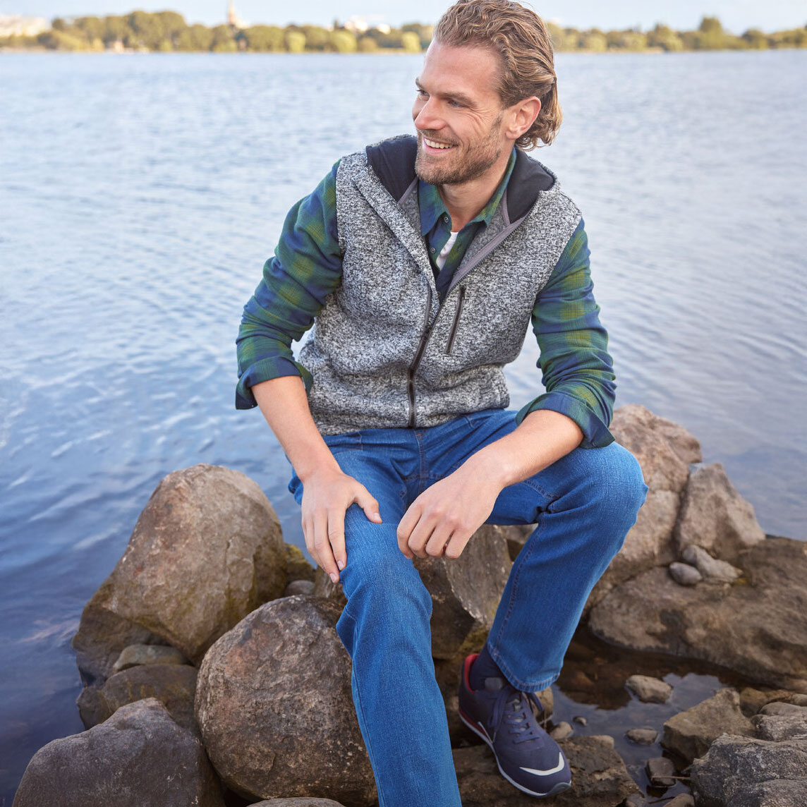 Graue Weste über grünem Hemd & blauer Jeans. 