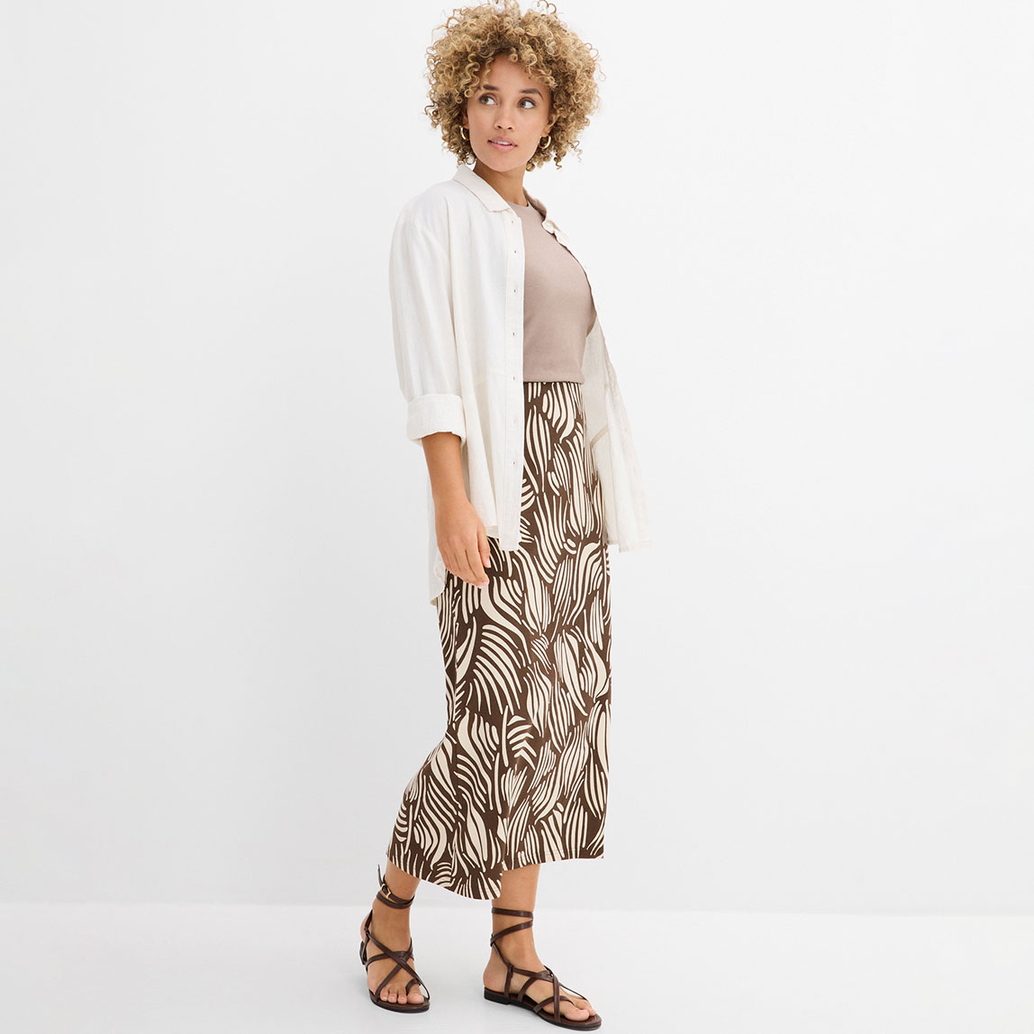 Elegante weiße Bluse kombiniert mit einem gemusterten Maxirock in Braun- und Beigetönen.