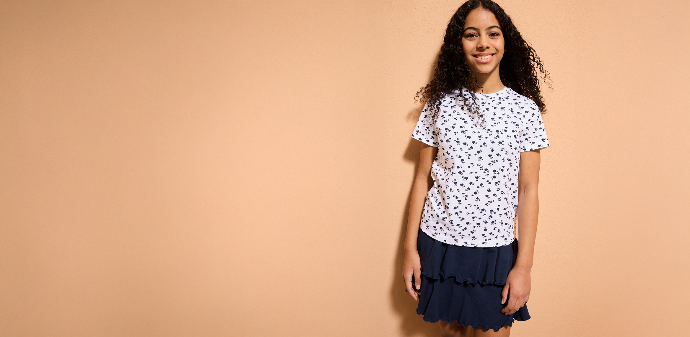 Ein Mädchen trägt ein weißes T-Shirt mit Muster.