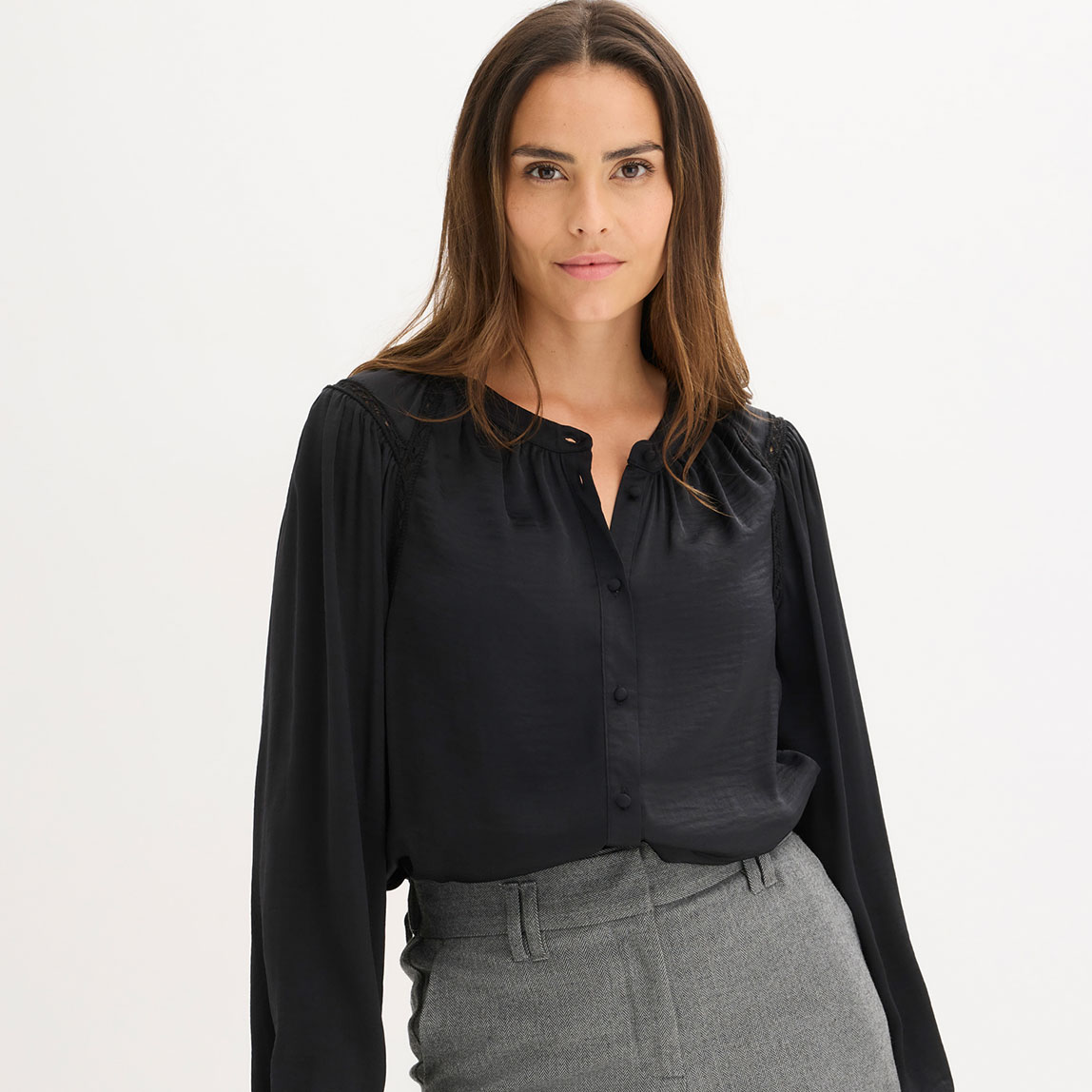Elegante schwarze Bluse mit V-Ausschnitt, kombiniert mit einer grauen Hose.