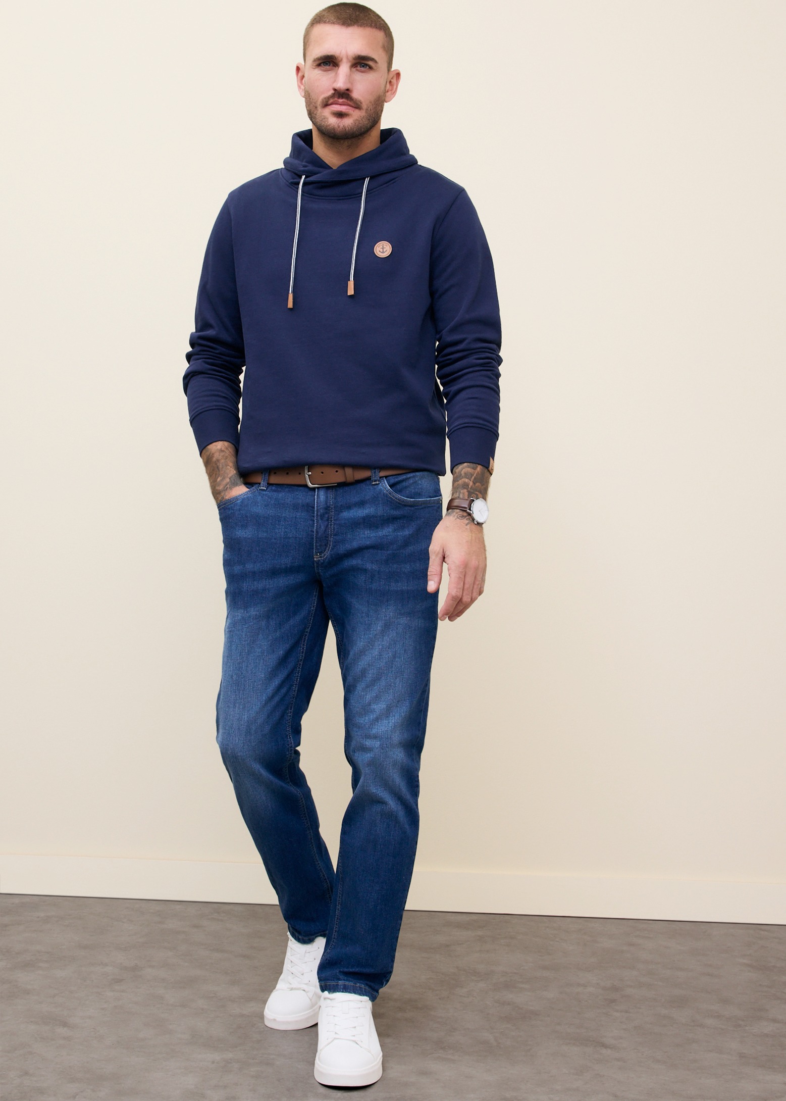 Dunkelblauer Kapuzenpullover, bequeme Jeans und weißen Sneaker.