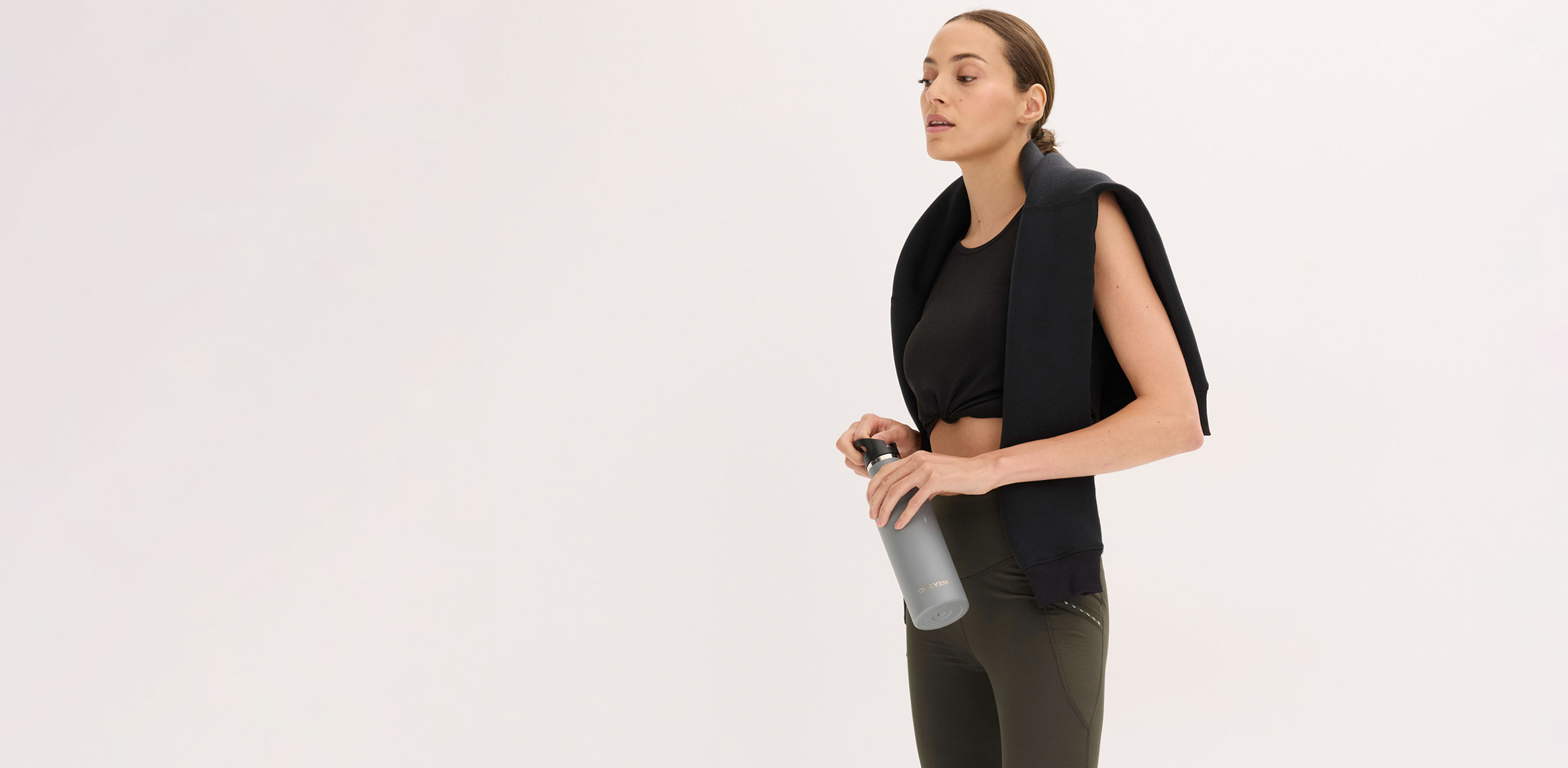 Schwarzes Sport-Top kombiniert mit olivgrüner Leggings.