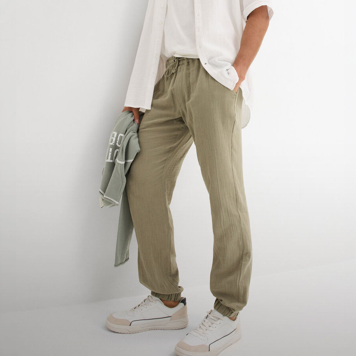 Entspannte olivgrüne Hose mit weißem Oberteil und hellem Sweatshirt.